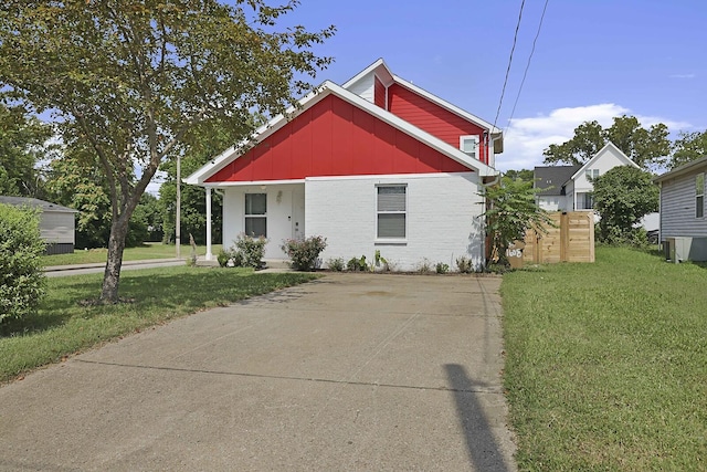 view of front of house with brick siding, board and batten siding, covered porch, and a front yard