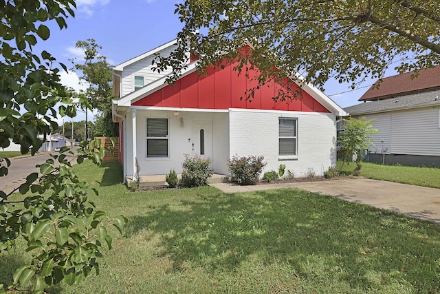 bungalow-style home with brick siding, board and batten siding, and a front lawn