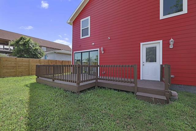 rear view of property with a wooden deck, a yard, and fence