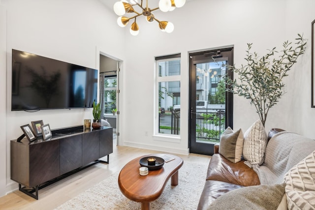 living room featuring light wood-style flooring, baseboards, and a chandelier