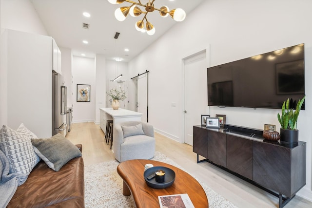 living area featuring visible vents, light wood finished floors, an inviting chandelier, recessed lighting, and a barn door