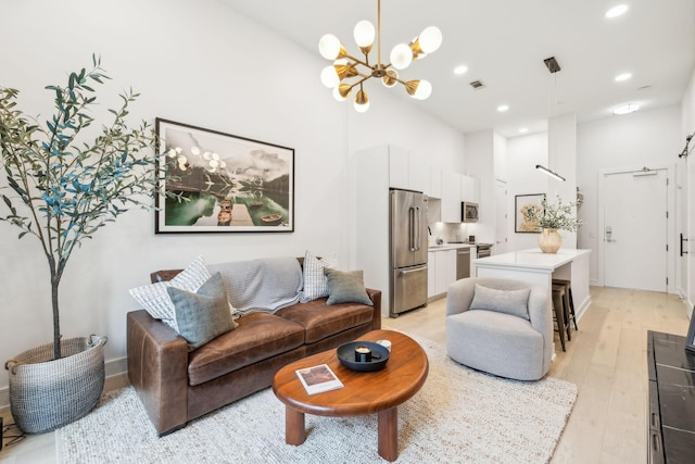 living area featuring visible vents, a chandelier, recessed lighting, light wood-style flooring, and a towering ceiling