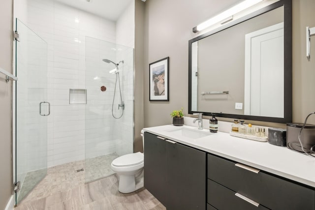 bathroom featuring a shower stall, toilet, and vanity