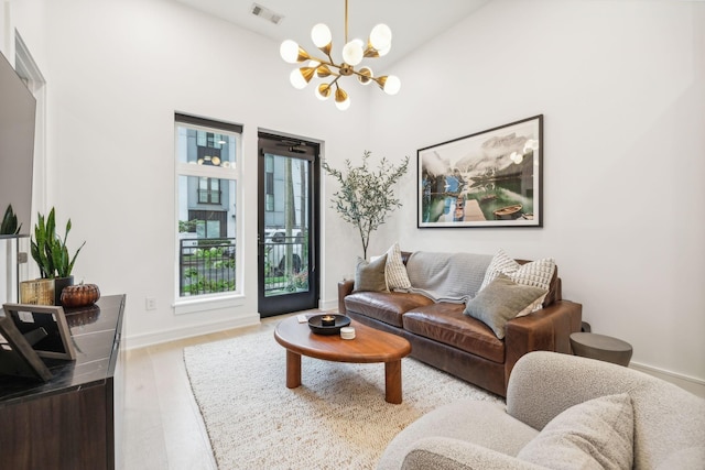 living room with a notable chandelier, visible vents, baseboards, and wood finished floors