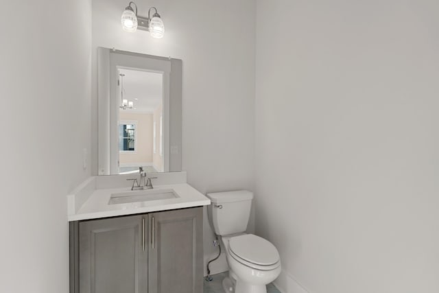 half bathroom featuring toilet, vanity, and baseboards