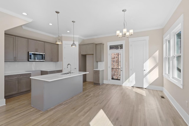 kitchen with stainless steel microwave, gray cabinetry, light wood-type flooring, and a sink