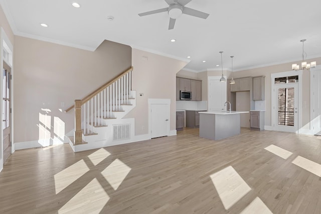 unfurnished living room featuring light wood finished floors, visible vents, stairs, and baseboards