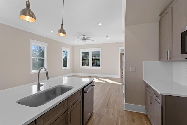 kitchen featuring a sink, crown molding, pendant lighting, light countertops, and stainless steel dishwasher