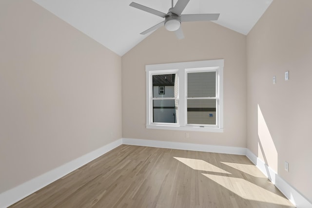 empty room with vaulted ceiling, ceiling fan, baseboards, and wood finished floors