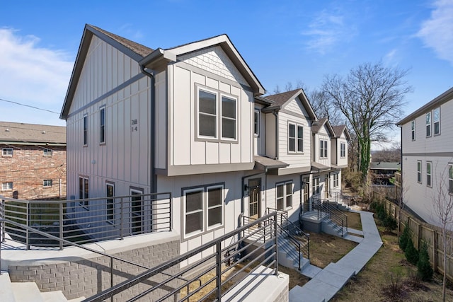 back of property with a residential view, board and batten siding, and fence