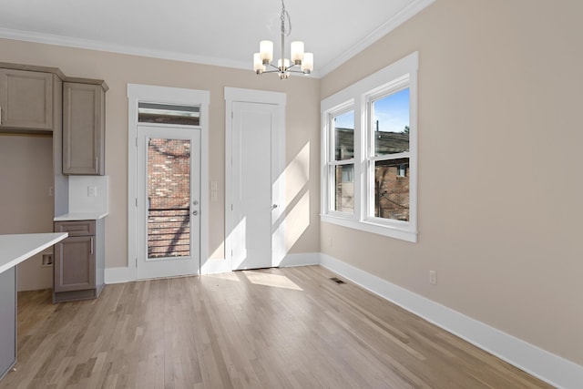 unfurnished dining area with light wood-style flooring, an inviting chandelier, baseboards, and ornamental molding