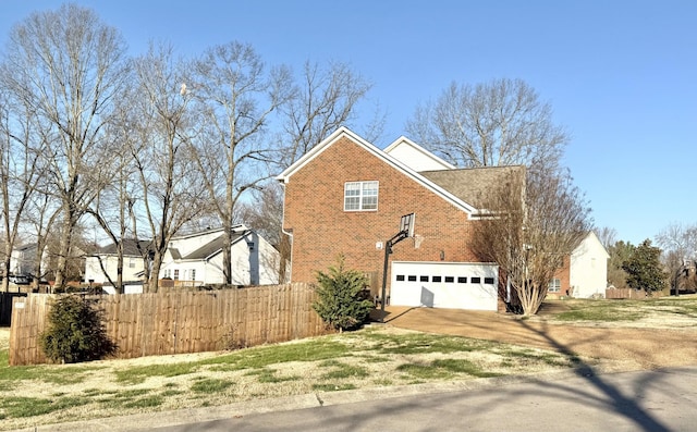 view of side of home featuring brick siding, an attached garage, fence, a lawn, and driveway