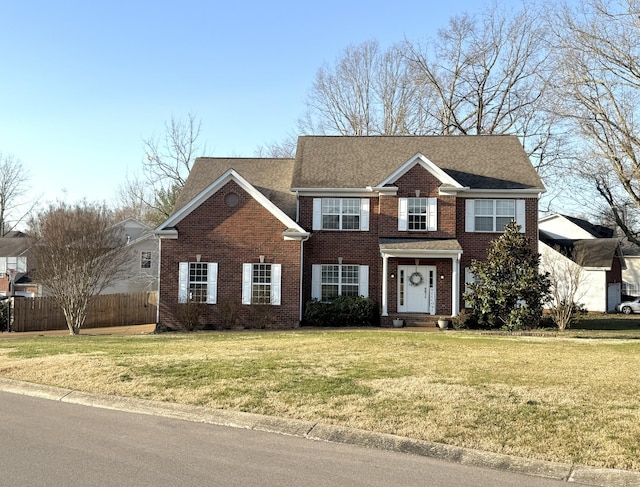 view of front of house with brick siding, a front yard, and fence