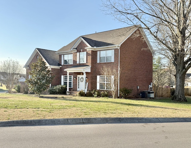 view of front of home with brick siding, a front lawn, and fence