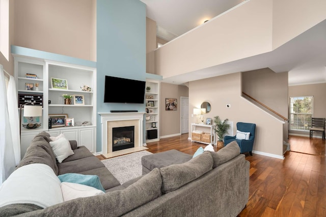 living room featuring hardwood / wood-style flooring, a high ceiling, baseboards, and a high end fireplace