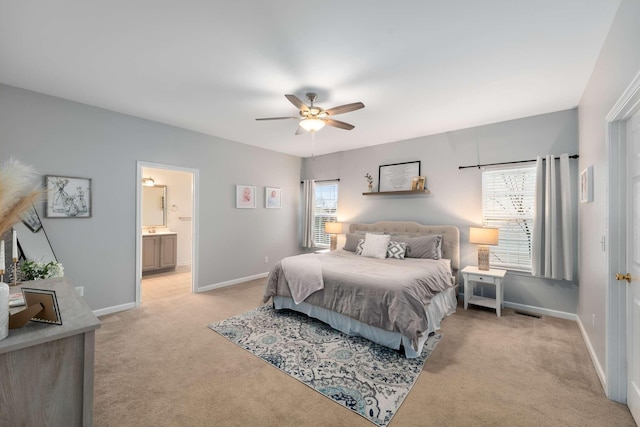 bedroom featuring light colored carpet, connected bathroom, baseboards, and ceiling fan