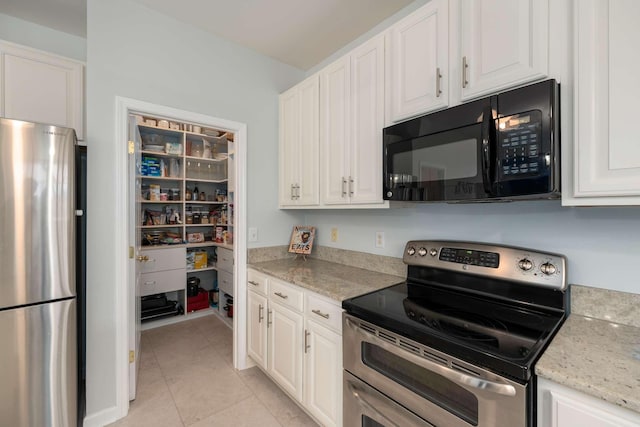 kitchen featuring light tile patterned floors, light stone countertops, appliances with stainless steel finishes, and white cabinets