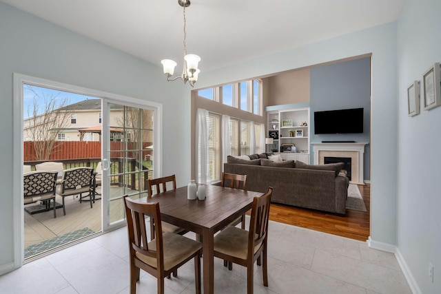 dining room featuring an inviting chandelier, light tile patterned flooring, a fireplace, and baseboards