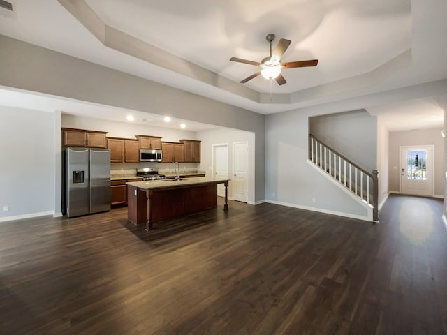 kitchen with dark wood finished floors, appliances with stainless steel finishes, baseboards, and a tray ceiling