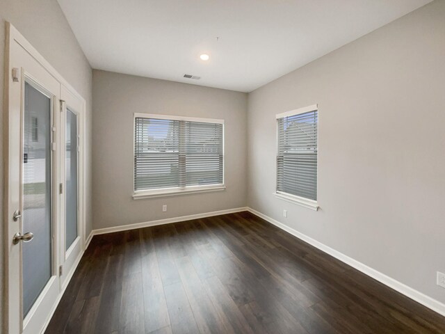 spare room featuring baseboards, visible vents, and dark wood-style flooring