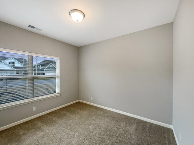 carpeted spare room featuring baseboards and visible vents