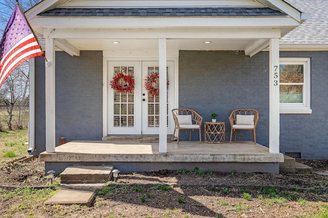 entrance to property featuring french doors and roof with shingles