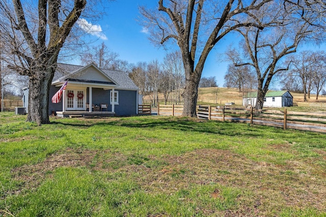 view of yard with central air condition unit, an outbuilding, fence, french doors, and a rural view