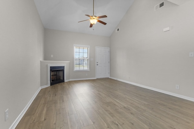 unfurnished living room with visible vents, ceiling fan, a fireplace, wood finished floors, and high vaulted ceiling