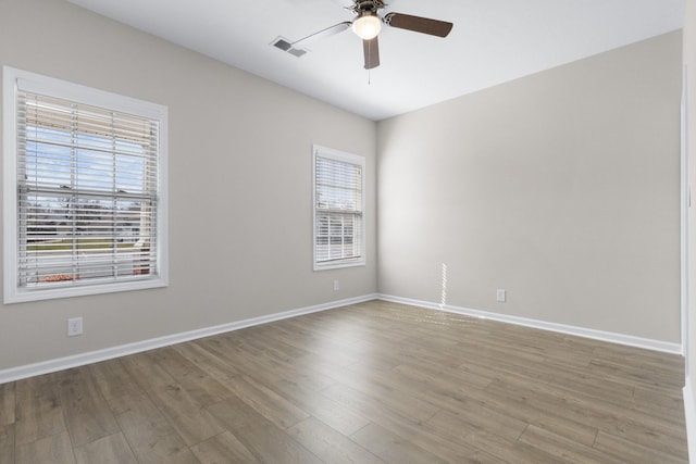 empty room with baseboards, wood finished floors, visible vents, and ceiling fan