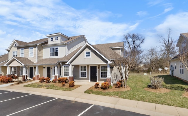 view of front of house featuring uncovered parking, a front lawn, and a shingled roof