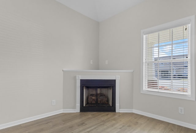 unfurnished living room featuring a fireplace, wood finished floors, and baseboards