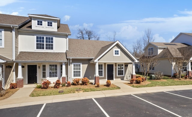 view of property featuring uncovered parking and a shingled roof