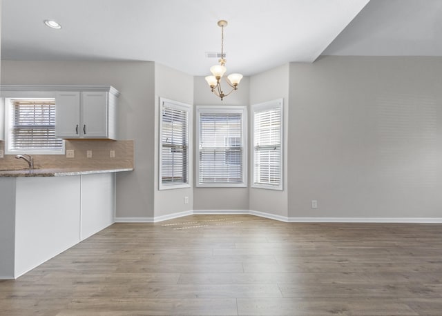 kitchen with visible vents, backsplash, wood finished floors, an inviting chandelier, and baseboards