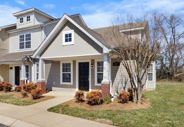 view of front of property featuring a front yard, brick siding, and a shingled roof