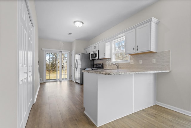 kitchen featuring decorative backsplash, wood finished floors, a wealth of natural light, and stainless steel appliances