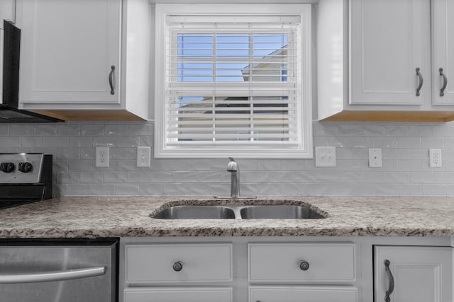 kitchen with a sink, light stone countertops, backsplash, and white cabinetry