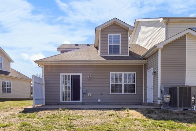 rear view of house featuring a patio, central air condition unit, a yard, and roof with shingles