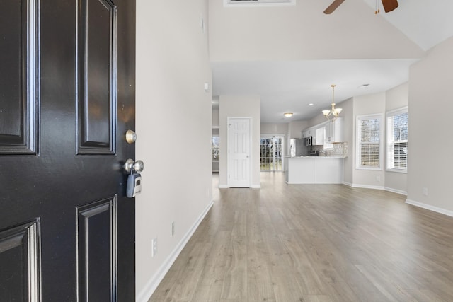 entryway featuring visible vents, baseboards, vaulted ceiling, light wood-style floors, and a ceiling fan