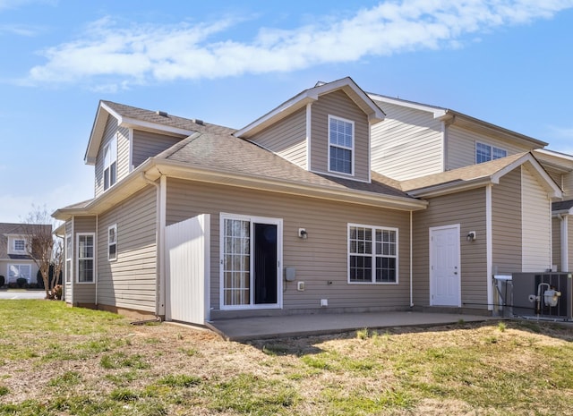 back of property featuring a yard, a patio area, and roof with shingles