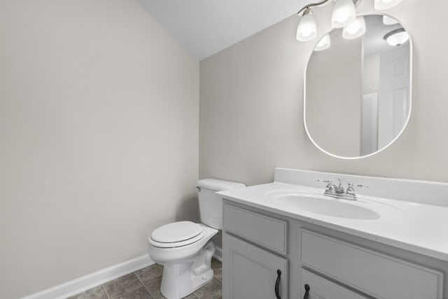 bathroom with baseboards, toilet, vaulted ceiling, tile patterned floors, and vanity