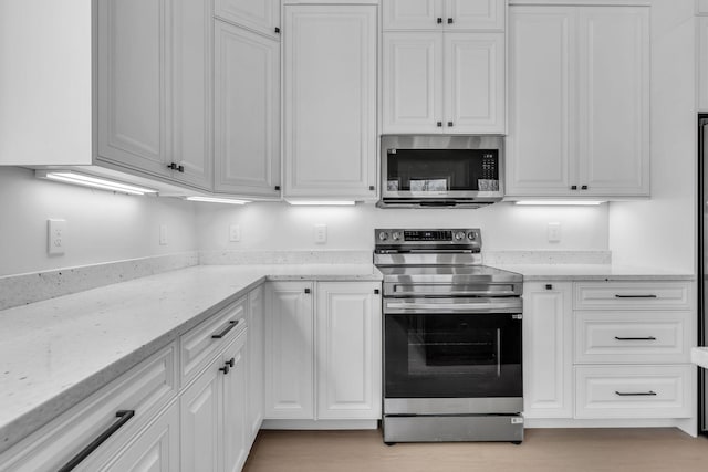 kitchen with white cabinetry, light stone countertops, and appliances with stainless steel finishes