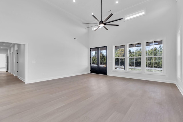 unfurnished living room featuring a ceiling fan, wood finished floors, french doors, a high ceiling, and baseboards