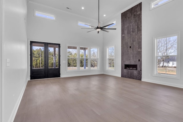 unfurnished living room with wood finished floors, a fireplace, baseboards, and french doors