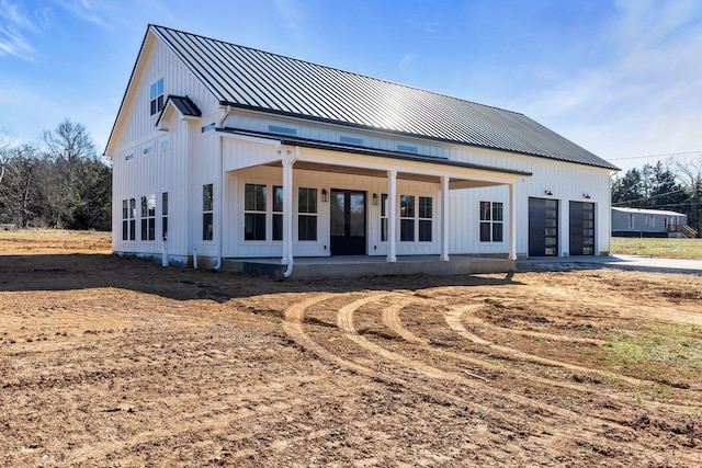 back of house featuring metal roof, an attached garage, and a standing seam roof