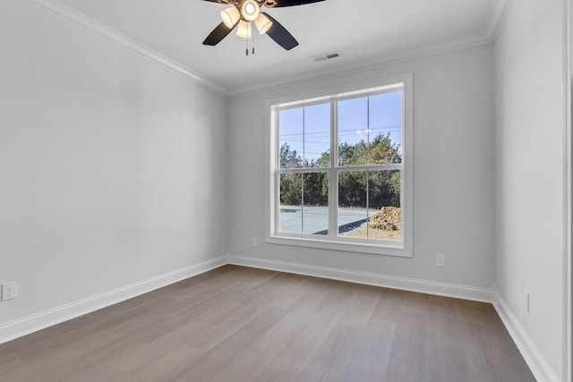 empty room with dark wood finished floors, visible vents, crown molding, and baseboards