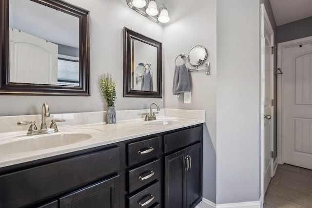 full bath featuring double vanity, wood finished floors, and a sink