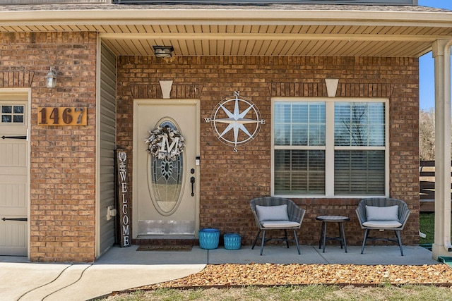 doorway to property featuring brick siding, a porch, and an attached garage