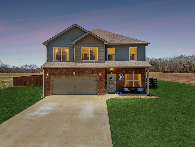 traditional home with driveway, fence, a yard, an attached garage, and brick siding