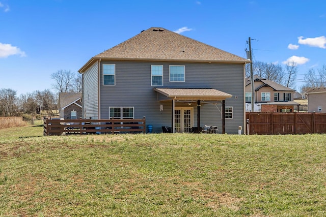 back of house with a yard, roof with shingles, ceiling fan, and fence