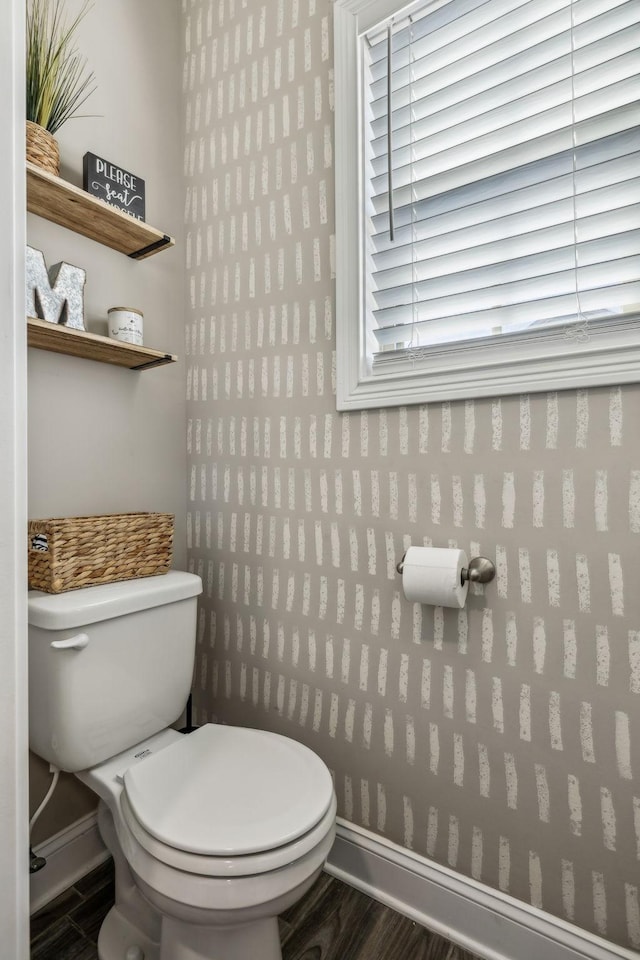 bathroom with baseboards, toilet, and wallpapered walls